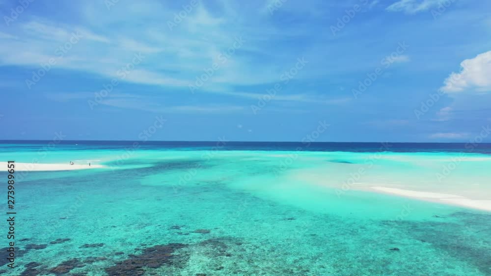 Aerial perspective of the turquoise Caribbean Sea with sandbanks and some rocks. The blue ocean in the background with a blue sky. Truck left, wide angle. Aerial perspective of the turquoise Caribbean Sea with sandbanks and some rocks. The blue ocean in the background with a blue sky. Truck left, wide angle.