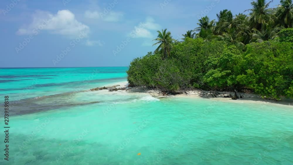 Aerial perspective. Flight next to the coast of a tropical island with palm trees on it. Turquoise water of the Caribbean Sea in front of it. Truck right. Aerial perspective. Flight next to the coast of a tropical island with palm trees on it. Turquoise water of the Caribbean Sea in front of it. Truck right.