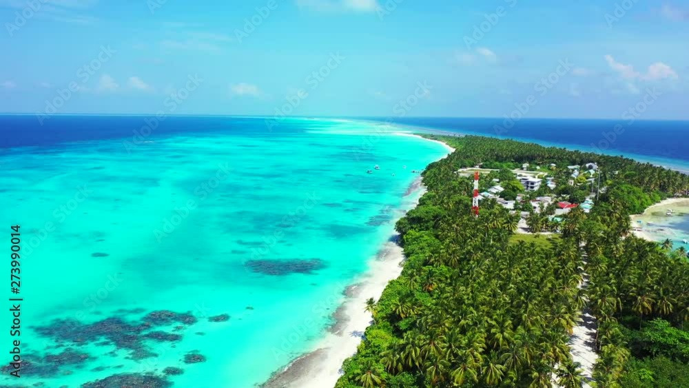 Aerial view of an island with palm trees and a village on it. Surrounded by turquoise water. Dolly in. Aerial view of an island with palm trees and a village on it. Surrounded by turquoise water. Dolly in.