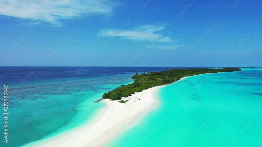 A long sandbank turns into an island with trees on it. In the turquoise Caribbean Sea with a blue sky above. Slow pedestal up, aerial. A long sandbank turns into an island with trees on it. In the turquoise Caribbean Sea with a blue sky above. Slow pedestal up, aerial.