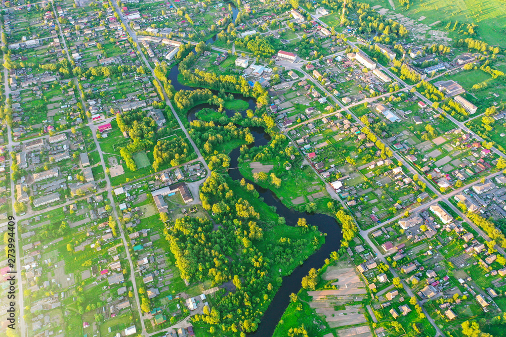 Aerial view landscape of winding small river among the small town, stream in green field.