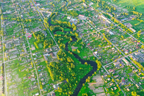Aerial view landscape of winding small river among the small town, stream in green field.