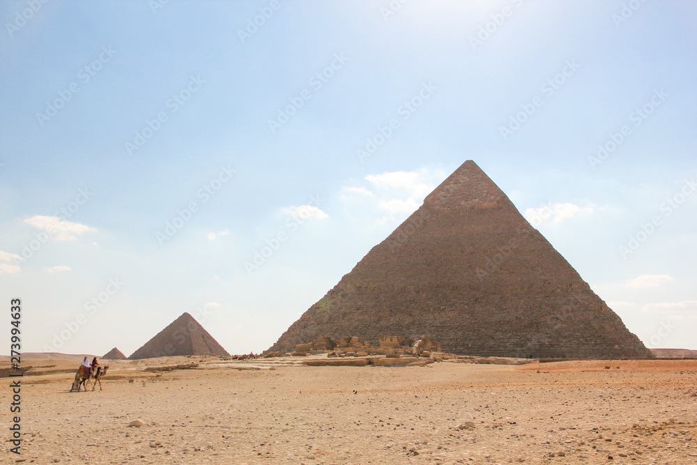 View from the desert on a series of pyramids, the three pyramids of the Giza complex with marching riders
