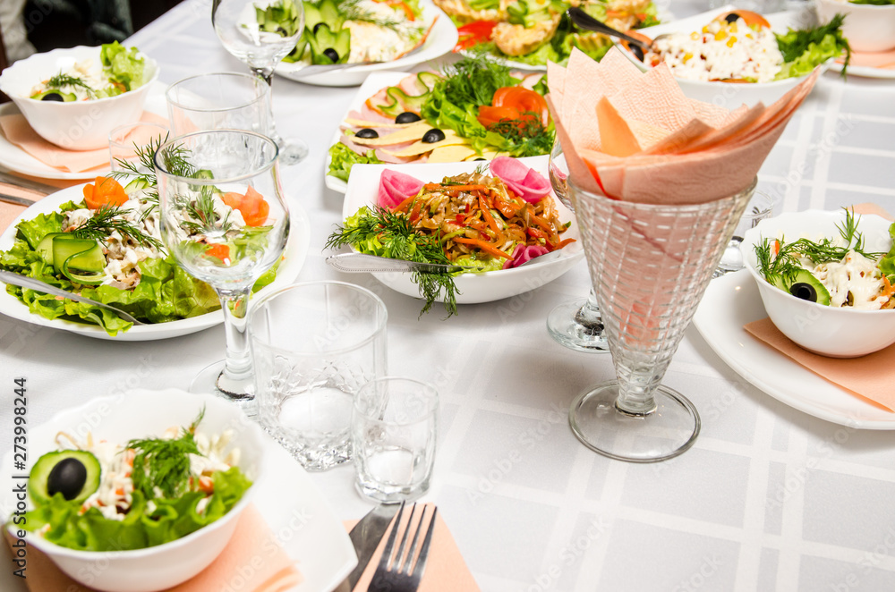 table lined with variety of dishes from which the centerpiece is dish of salad of pork ears, carrots, Bulgarian pepper, fresh cucumbers, lettuce, onions and greens seasoned with vegetable oil table lined with variety of dishes from which the centerpiece is dish of salad of pork ears, carrots, Bulgarian pepper, fresh cucumbers, lettuce, onions and greens seasoned with vegetable oil