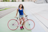 Cycling and fitness. Young beautiful fit woman with perfect body in sportswear with the bicycle outdoors on the track. Sportive and healthy lifestyle, cyclist working out, training, fashion, beauty.
