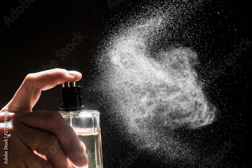 spraying perfume on dark background, closeup