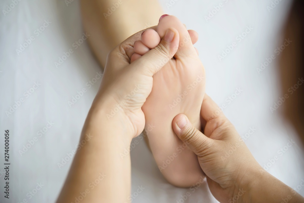 Woman receiving foot massage service from masseuse close up at hand and foot - relax in foot massage therapy service concept Woman receiving foot massage service from masseuse close up at hand and foot - relax in foot massage therapy service concept