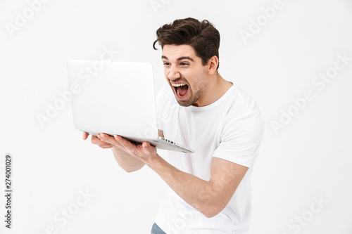 Screaming young man posing isolated over white wall using laptop computer.