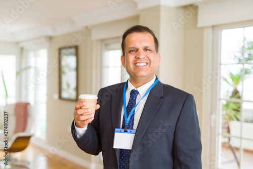 Middle age business man drinking a cup of coffee wearing identification card