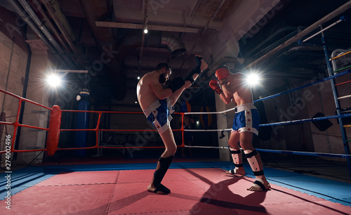 Two anger kickboxers training kickboxing in the ring at the health club