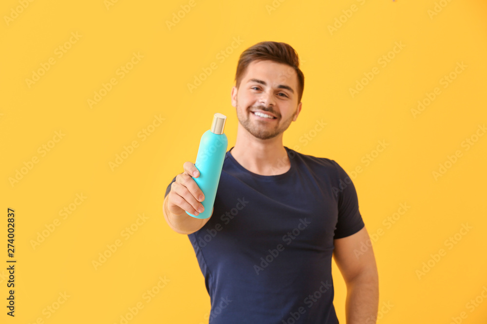 Handsome man with bottle of shampoo on color background Handsome man with bottle of shampoo on color background