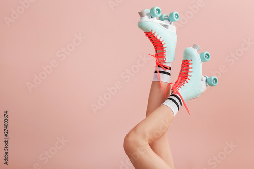 Legs of woman in vintage roller skates on color background photo