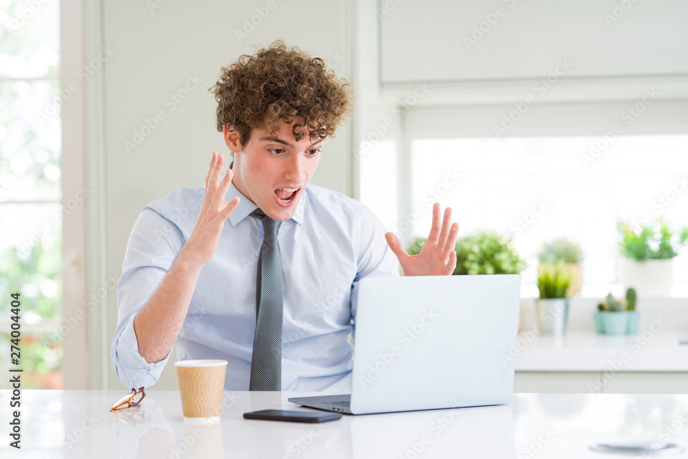 Young business man working with computer laptop at the office very happy and excited, winner expression celebrating victory screaming with big smile and raised hands Young business man working with computer laptop at the office very happy and excited, winner expression celebrating victory screaming with big smile and raised hands