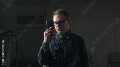 Man in glasses watches video on his smartphone in the dark environment, people with gadgets, surfing the internet, looking through the social networks, chat in the mobila phone, 4k UHD Prores 422 HQ photo