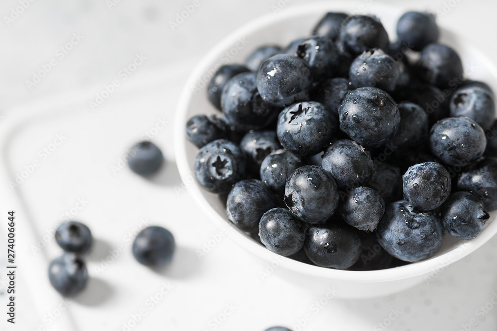 Blueberries in a white bowl on a light background