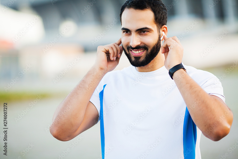 Fototapeta premium Sport man using headphones for listening music on morning run in park