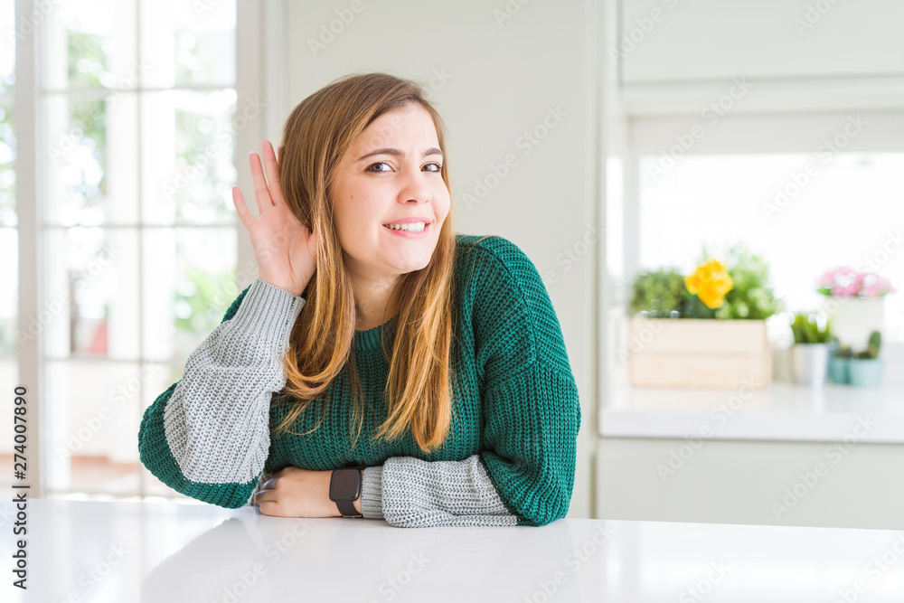 Young beautiful plus size woman wearing casual striped sweater smiling with hand over ear listening an hearing to rumor or gossip. Deafness concept. Young beautiful plus size woman wearing casual striped sweater smiling with hand over ear listening an hearing to rumor or gossip. Deafness concept.