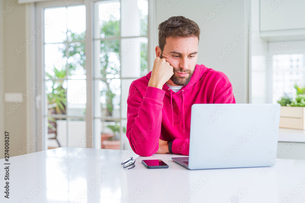 Handsome man working using computer laptop thinking looking tired and bored with depression problems with crossed arms. Handsome man working using computer laptop thinking looking tired and bored with depression problems with crossed arms.