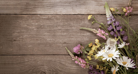 Wild flowers on old grunge wooden background (chamomile lupine dandelions thyme mint bells rape)