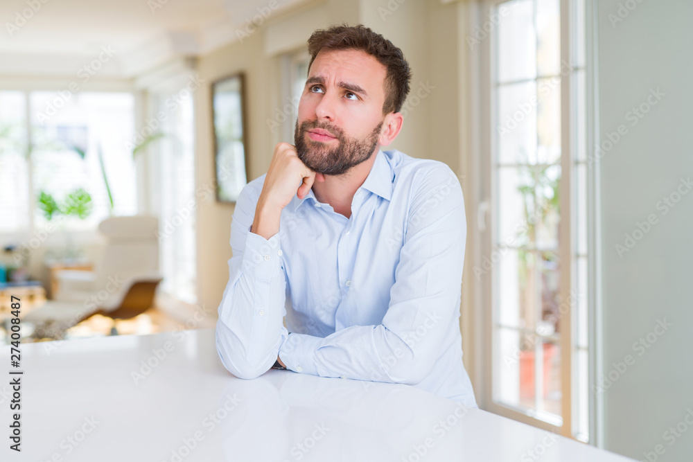 Handsome business man with hand on chin thinking about question, pensive expression. Smiling with thoughtful face. Doubt concept.