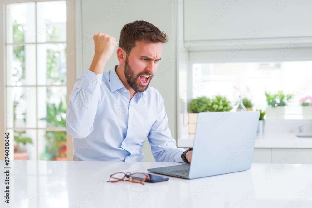Handsome business man working using computer laptop annoyed and frustrated shouting with anger, crazy and yelling with raised hand, anger concept