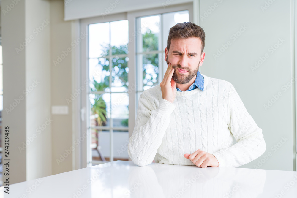 Handsome man wearing casual sweater touching mouth with hand with painful expression because of toothache or dental illness on teeth. Dentist concept.
