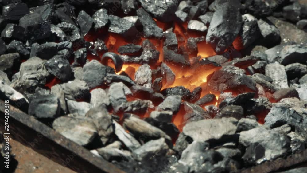 Close Up of Hot Metal Bar Being Heated in a Coal Forge in the Blacksmith Shop with Flame. Metal parts are being heated in the furnace and prepared for forging in blacksmith workshop Close Up of Hot Metal Bar Being Heated in a Coal Forge in the Blacksmith Shop with Flame. Metal parts are being heated in the furnace and prepared for forging in blacksmith workshop
