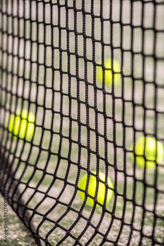 Tennis Balls Behind Padel Net Indoors.