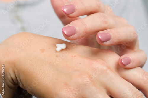 Close up of applying skin cream on female hand