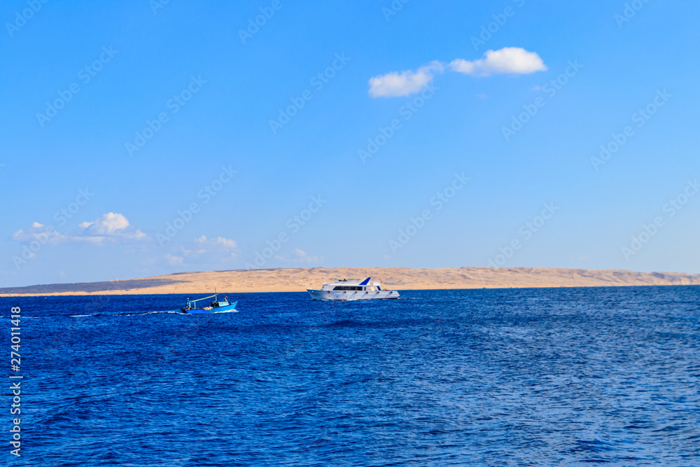 Old fishing boat and white luxury yacht sails in the Red sea, Egypt