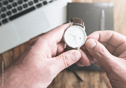 Valokuva man setting his wristwatch against laptop computer and personal organizer on woo