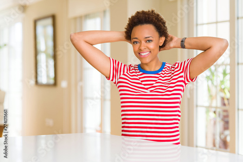 Young beautiful african american woman at home Relaxing and stretching with arms and hands behind head and neck  smiling happy