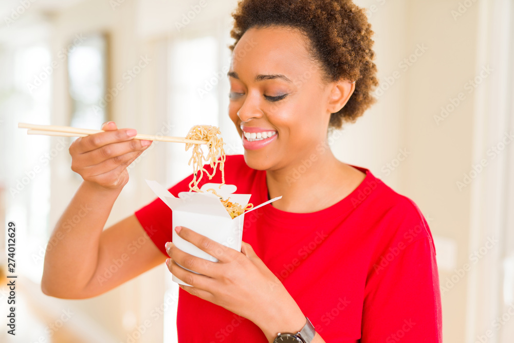 Beautiful young african american woman eating noodles using choopsticks Beautiful young african american woman eating noodles using choopsticks