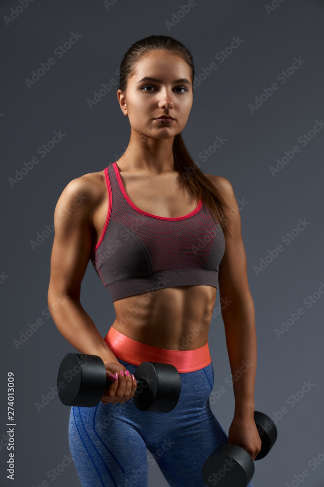 Active girl with perfect body shape keeping black dumbbells Active girl with perfect body shape keeping black dumbbells