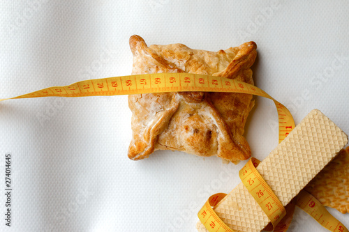 Yellow Plastic tape measure on the white waffles and baked apple pie. fitness, nutritionist, dietitian, fighting diabetes, obesity and cholesterol.