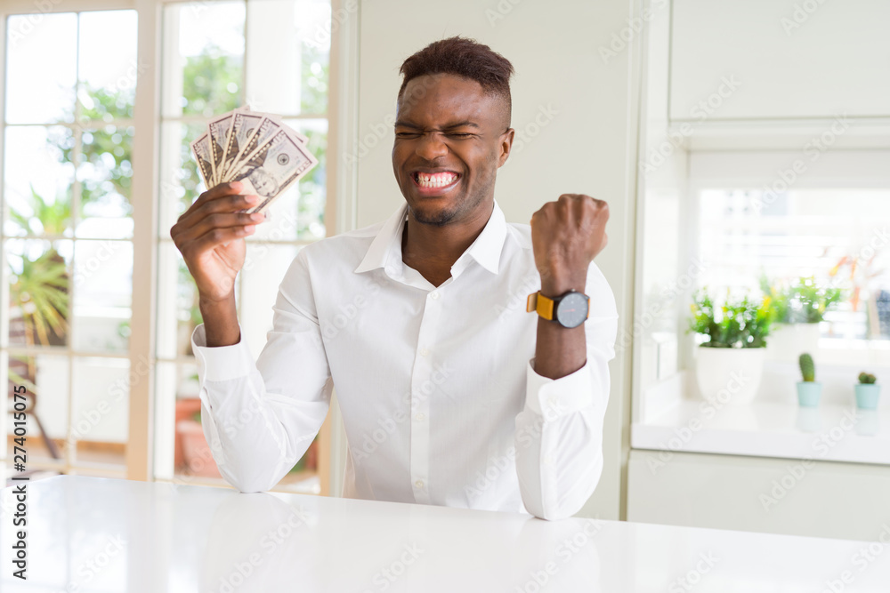 African american man holding fifty dollars bank notes screaming proud and celebrating victory and success very excited, cheering emotion African american man holding fifty dollars bank notes screaming proud and celebrating victory and success very excited, cheering emotion