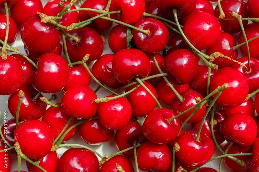 a heap of red summer sweet cherries scattered on table, texture with view from above. Major commercial cherry orchards in Europe are in Turkey, Italy, Spain and other Mediterranean regions. a heap of red summer sweet cherries scattered on table, texture with view from above. Major commercial cherry orchards in Europe are in Turkey, Italy, Spain and other Mediterranean regions.