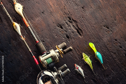 Fishing lures, hooks and accessories on darken wooden background.Top view.