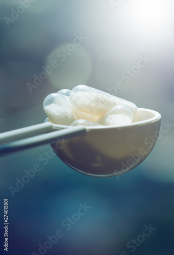 Closeup of white capsules on blue abstract background. pills in the spoon. Pharmaceutical industry. Fresh vitamin nutrition. Healthcare, medicine. Medical health care. Tablet overdose. Healthy food.