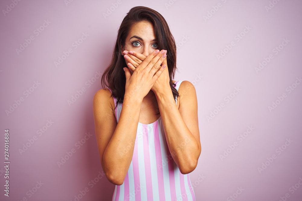 Young beautiful woman wearing striped pink swimsuit swimwear over pink isolated background shocked covering mouth with hands for mistake. Secret concept. Young beautiful woman wearing striped pink swimsuit swimwear over pink isolated background shocked covering mouth with hands for mistake. Secret concept.