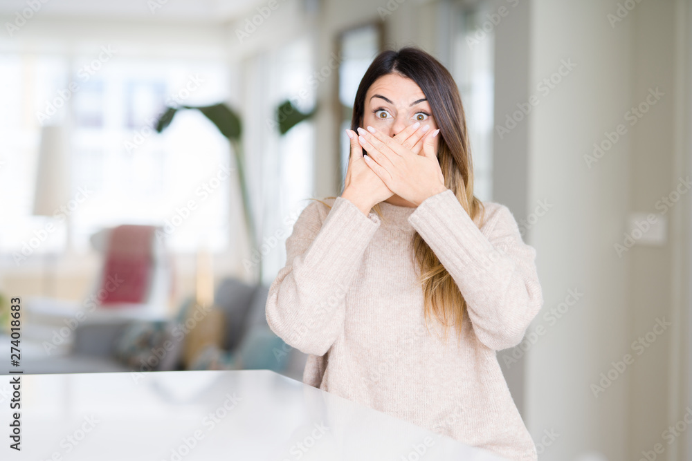 Young beautiful woman wearing winter sweater at home shocked covering mouth with hands for mistake. Secret concept. Young beautiful woman wearing winter sweater at home shocked covering mouth with hands for mistake. Secret concept.