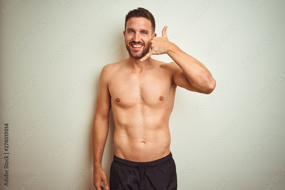 Young handsome shirtless man over isolated background smiling doing phone gesture with hand and fingers like talking on the telephone. Communicating concepts.