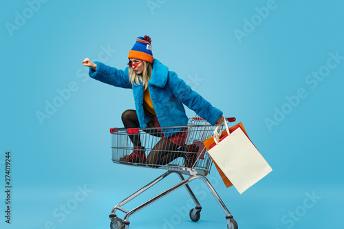 Young woman with shopping bags riding trolley photo