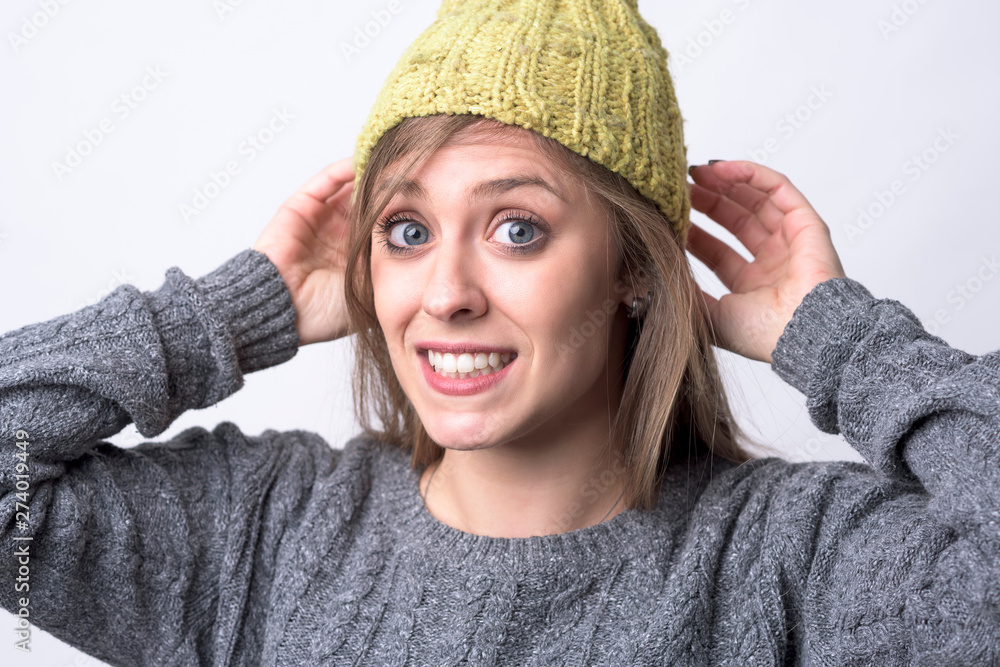 Playful funky expressive woman with yellow cap and cheesy grin smile at camera on light gray background. Playful funky expressive woman with yellow cap and cheesy grin smile at camera on light gray background.