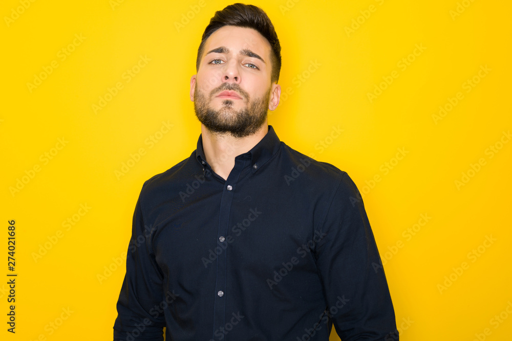 Obraz premium Young handsome man possing and modeling over yellow isolated background