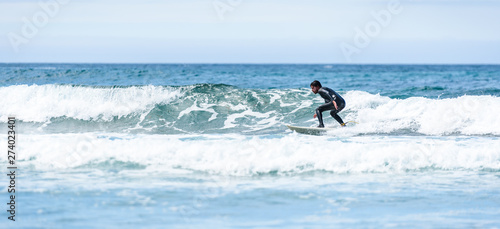 Photography Surfer guy surfing with surfboard on waves in Atlantic ocean.