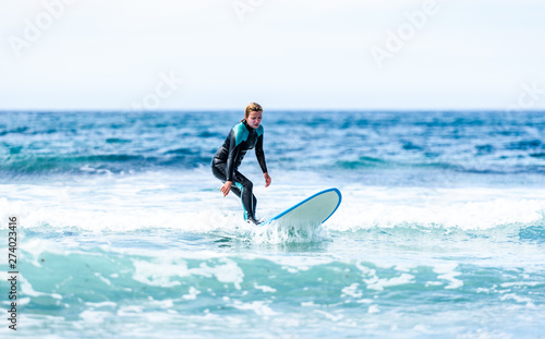 Surfer girl surfing with surfboard on waves in Atlantic ocean.
