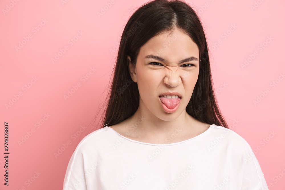 Portrait closeup of amusing happy girl with long dark hair having fun and sticking out her tongue Portrait closeup of amusing happy girl with long dark hair having fun and sticking out her tongue
