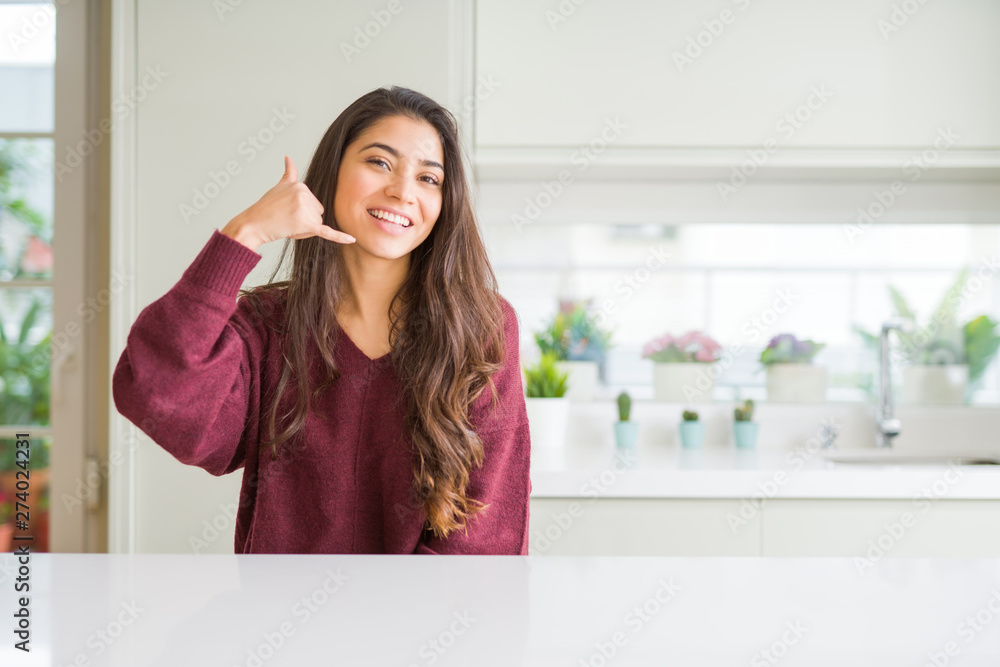 Young beautiful woman at home smiling doing phone gesture with hand and fingers like talking on the telephone. Communicating concepts.