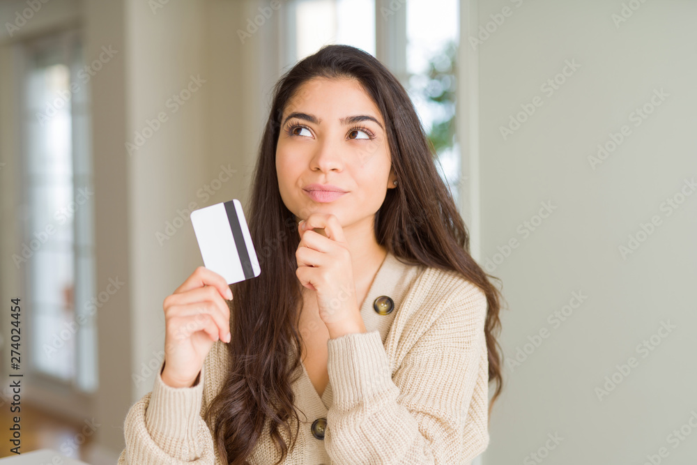 Young woman holding credit card as payment serious face thinking about question, very confused idea Young woman holding credit card as payment serious face thinking about question, very confused idea